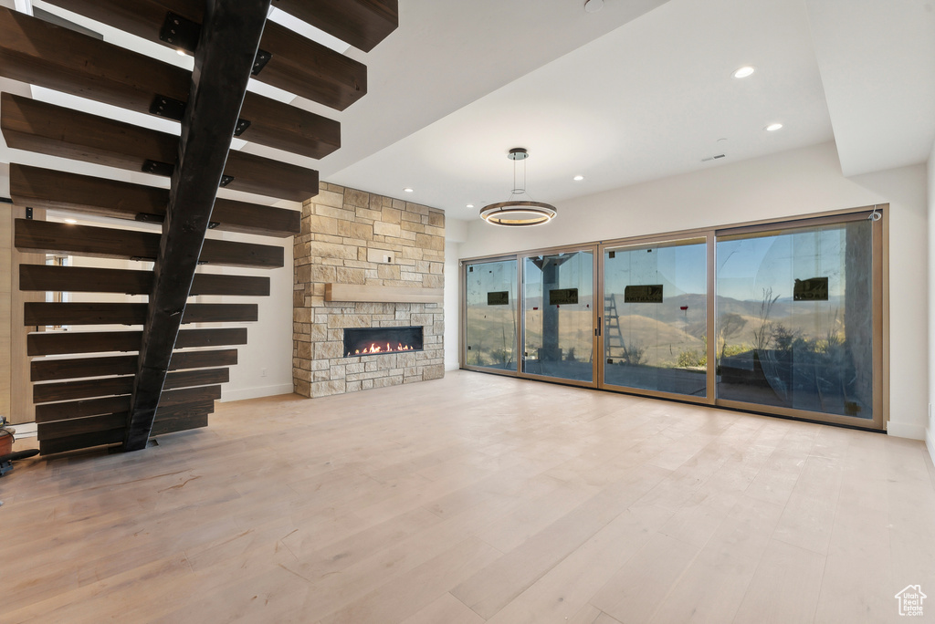 Unfurnished living room featuring a stone fireplace and light hardwood / wood-style floors