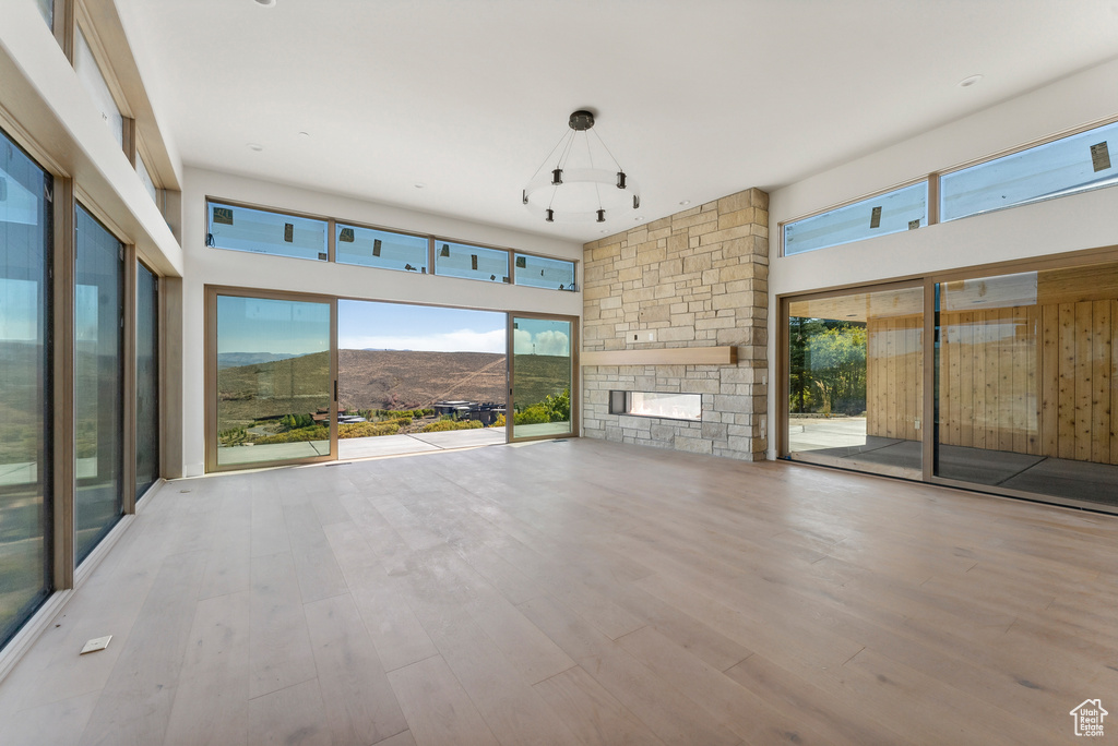 Unfurnished living room with a mountain view, a stone fireplace, a towering ceiling, and light hardwood / wood-style floors