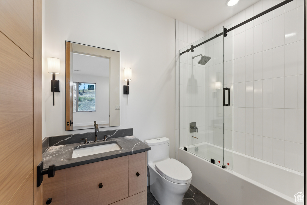 Full bathroom with vanity, enclosed tub / shower combo, toilet, and tile patterned floors