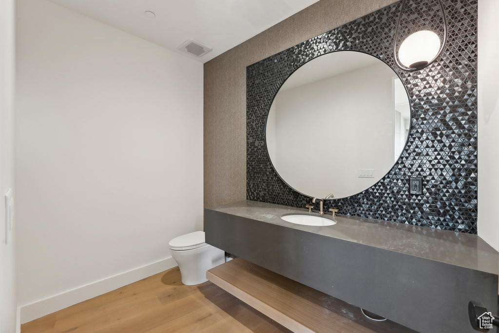 Bathroom with toilet, decorative backsplash, vanity, and wood-type flooring