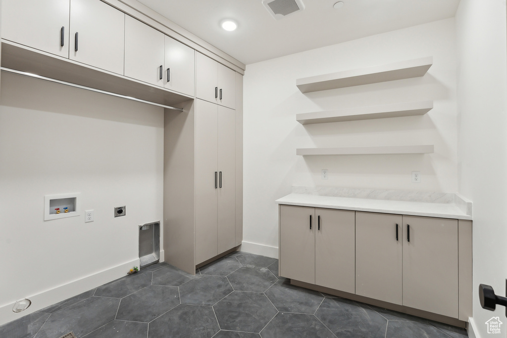 Laundry area featuring cabinets, hookup for a washing machine, dark tile patterned flooring, and electric dryer hookup