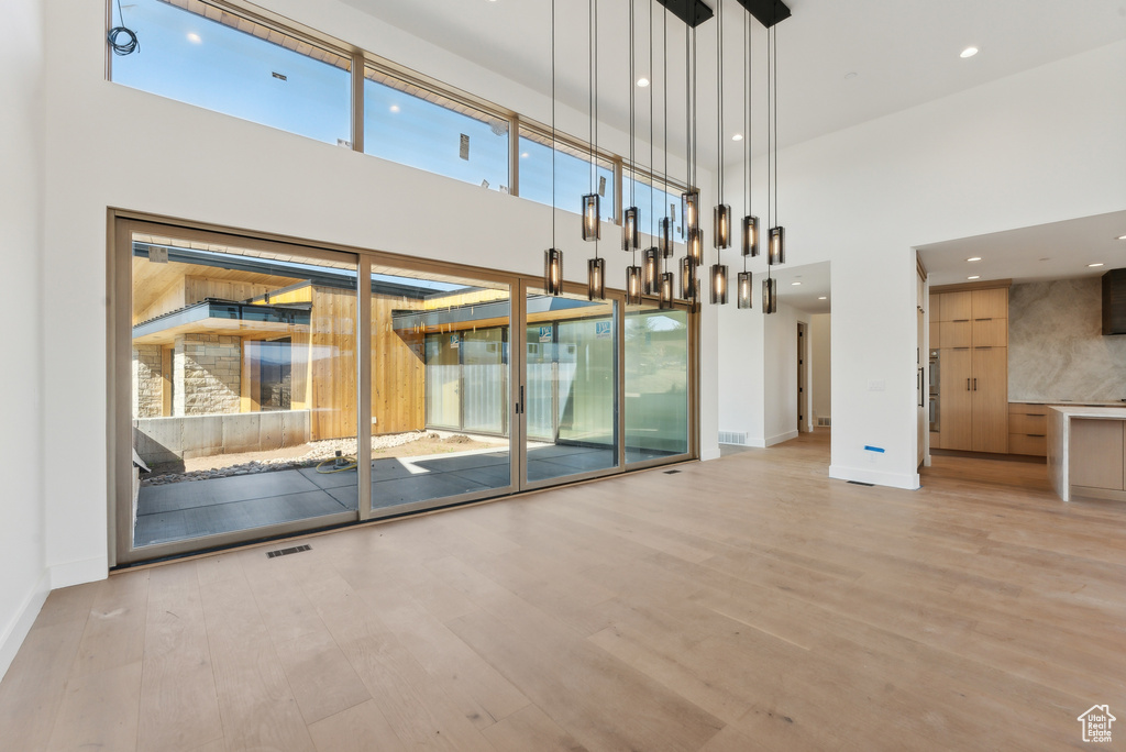 Unfurnished living room featuring a towering ceiling and wood-type flooring