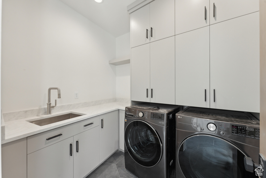 Washroom featuring cabinets, washer and dryer, sink, and dark tile patterned floors