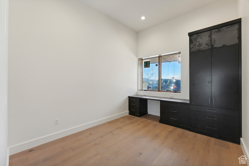 Unfurnished bedroom with light hardwood / wood-style flooring and built in desk