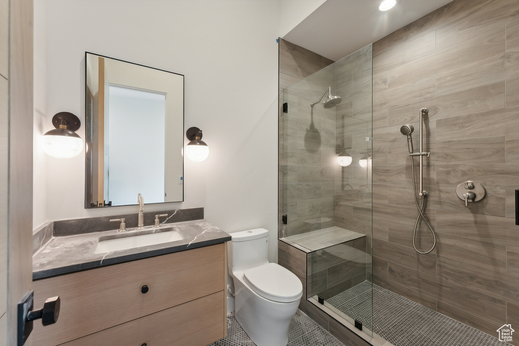 Bathroom with toilet, an enclosed shower, vanity, and tile patterned floors