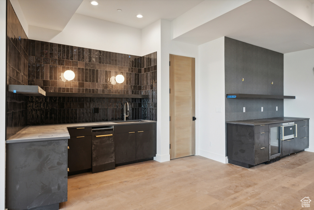 Kitchen featuring light hardwood / wood-style floors, decorative backsplash, sink, and tile walls