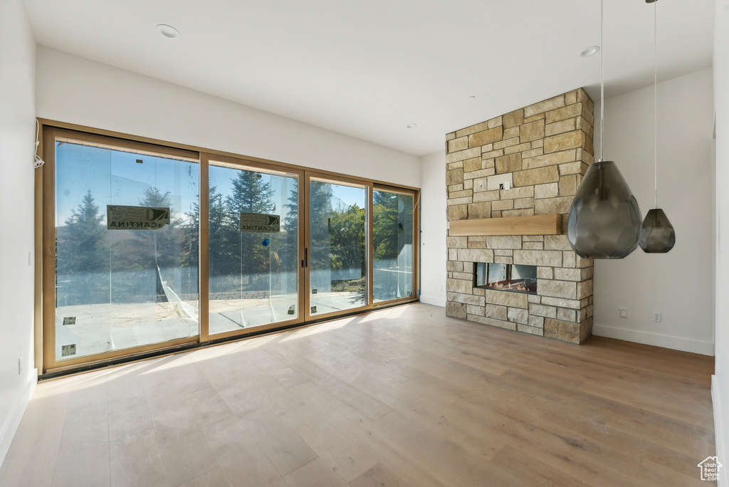 Unfurnished living room featuring a stone fireplace and wood-type flooring