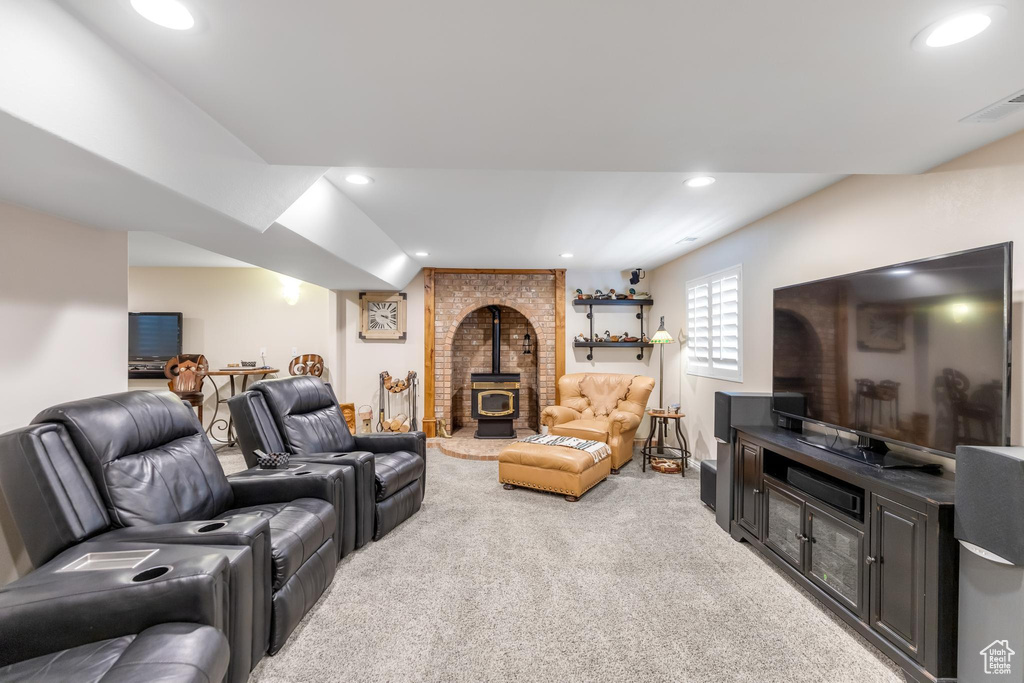 Living room featuring brick wall, light carpet, and a wood stove