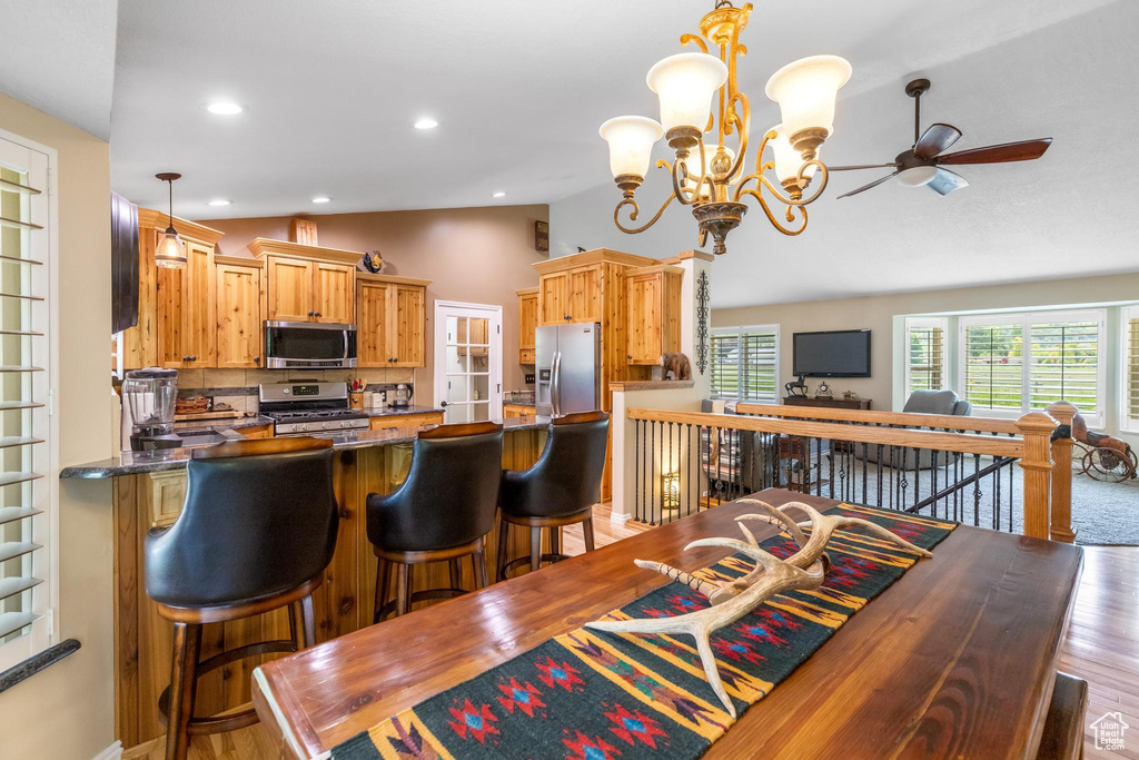 Kitchen with stainless steel appliances, vaulted ceiling, hardwood / wood-style floors, and pendant lighting