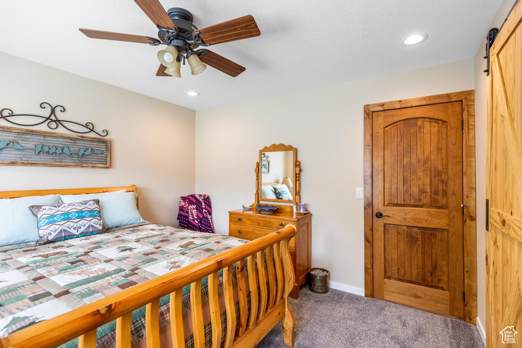 Carpeted bedroom with a barn door and ceiling fan