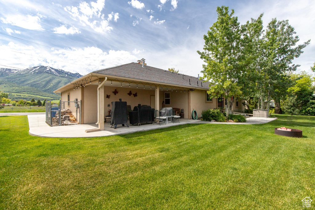 Rear view of house with a patio area, a mountain view, and a lawn