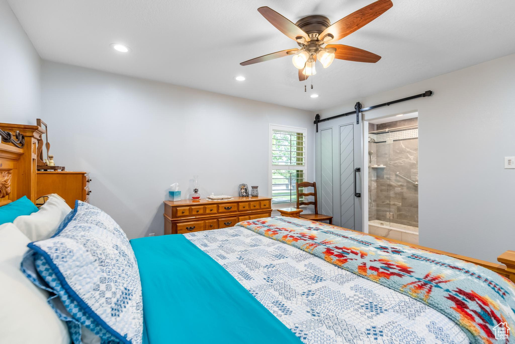 Bedroom featuring connected bathroom, a barn door, and ceiling fan