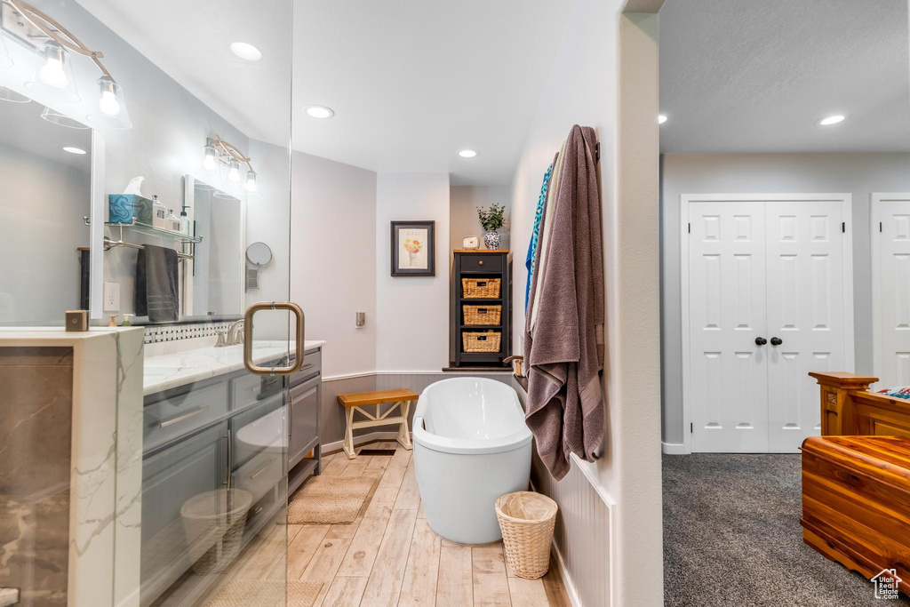 Bathroom featuring a bath to relax in, vanity, and hardwood / wood-style flooring