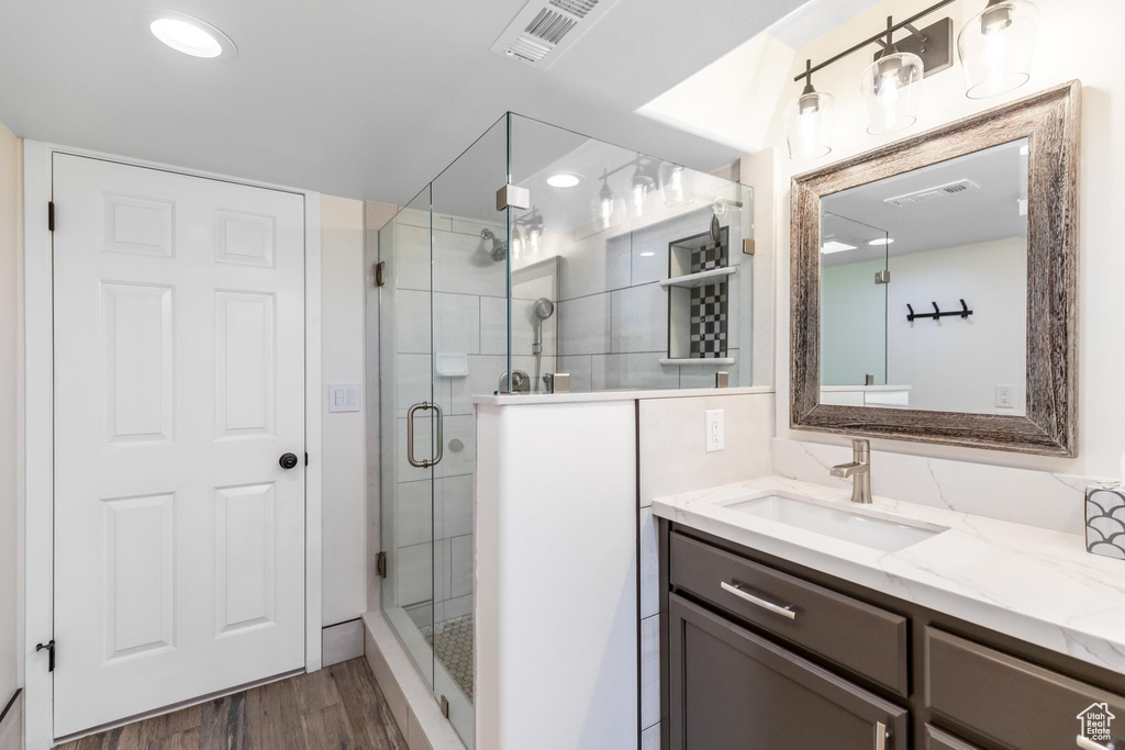 Bathroom featuring wood-type flooring, a shower with shower door, and vanity