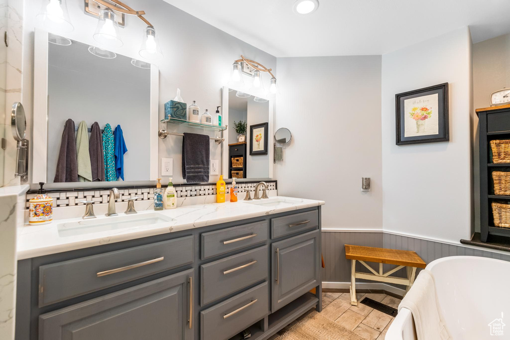 Bathroom featuring tile floors, backsplash, large vanity, and double sink