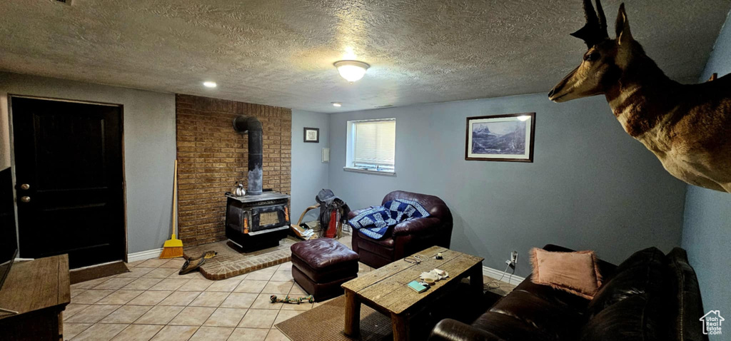 Tiled living room with brick wall, a textured ceiling, and a wood stove