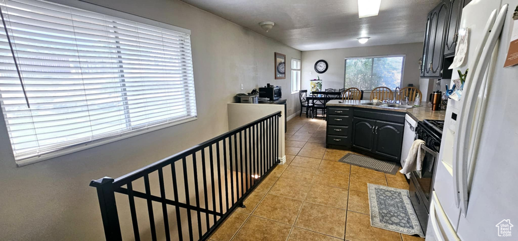 Kitchen with stainless steel range with gas cooktop, sink, white refrigerator, and light tile patterned floors