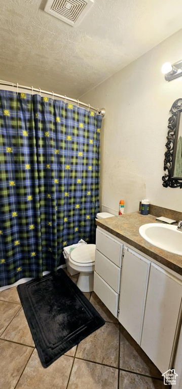 Bathroom with vanity, tile patterned flooring, toilet, and a textured ceiling