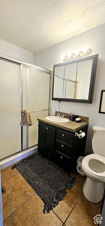 Bathroom with vanity, toilet, tile patterned floors, and an enclosed shower