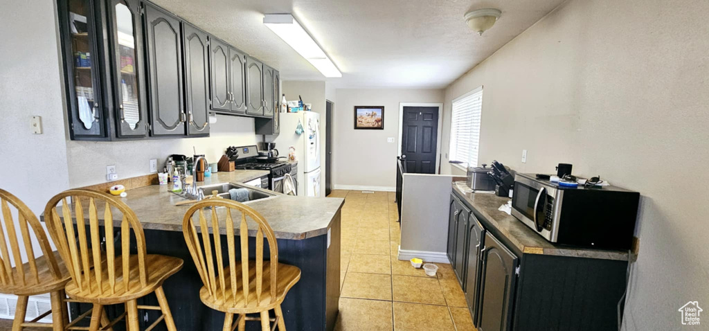 Kitchen featuring light tile patterned floors, kitchen peninsula, gray cabinets, stainless steel appliances, and sink