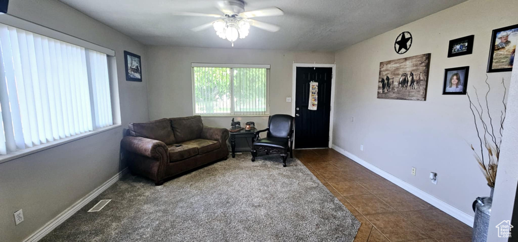 Living room with dark tile patterned floors and ceiling fan