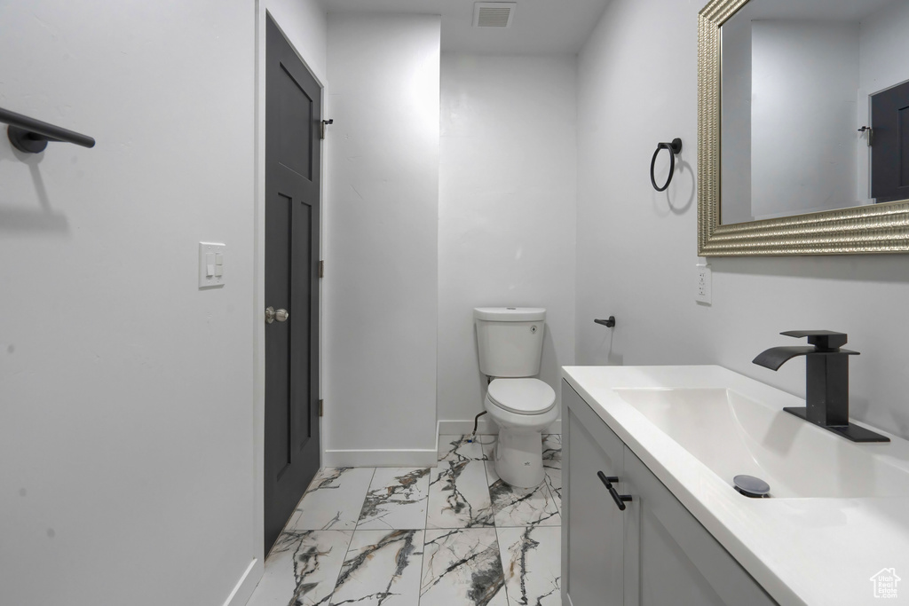 Bathroom with tile flooring, vanity with extensive cabinet space, and toilet