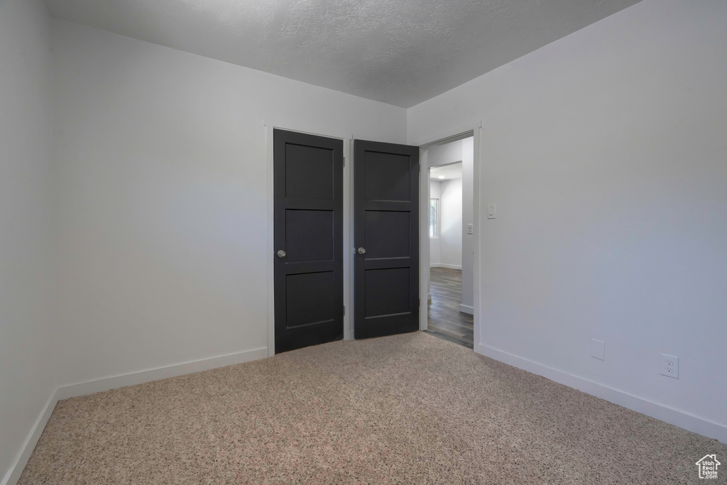 Empty room featuring a textured ceiling and carpet flooring