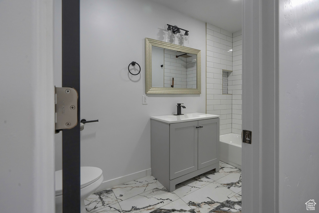 Full bathroom with tile floors, tiled shower / bath combo, vanity, and toilet