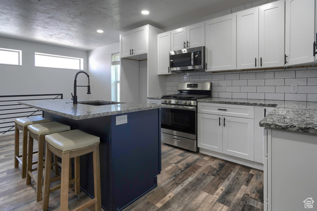 Kitchen with white cabinets, appliances with stainless steel finishes, and dark hardwood / wood-style floors