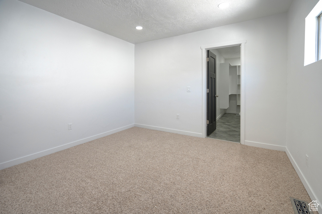 Empty room featuring carpet flooring and a textured ceiling