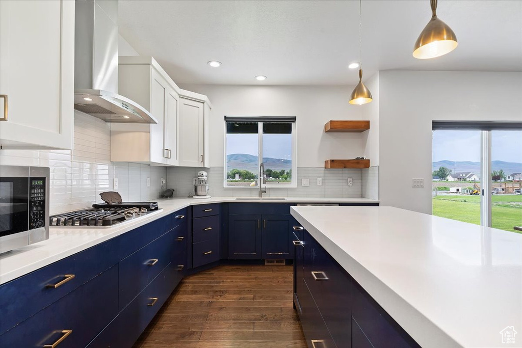 Kitchen with wall chimney range hood, white cabinetry, dark wood-type flooring, a mountain view, and tasteful backsplash