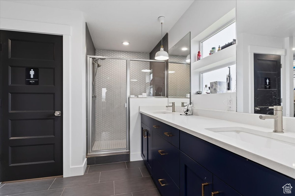 Bathroom with tile floors, a shower with door, and dual vanity