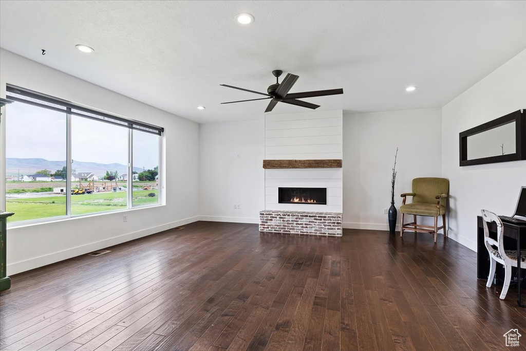 Unfurnished living room with ceiling fan, a mountain view, dark hardwood / wood-style flooring, and a fireplace