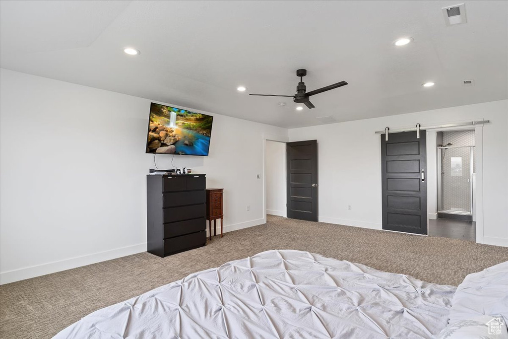 Bedroom featuring a barn door, carpet, and ceiling fan