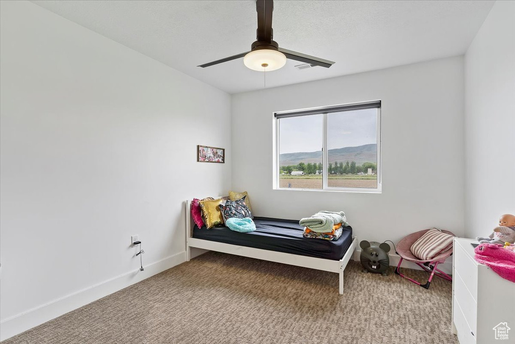 Bedroom featuring carpet, ceiling fan, and a mountain view