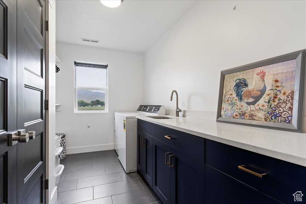 Washroom featuring washer and dryer, cabinets, sink, and dark tile floors