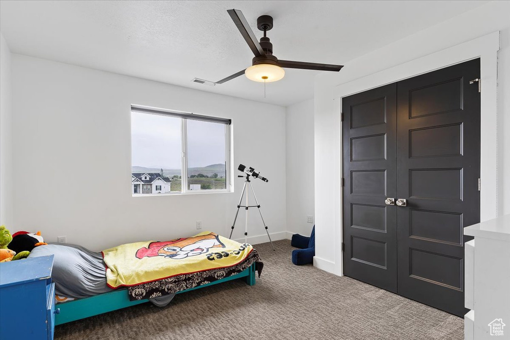 Carpeted bedroom featuring ceiling fan