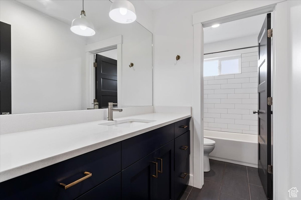 Full bathroom with tile floors, vanity, toilet, and tiled shower / bath combo