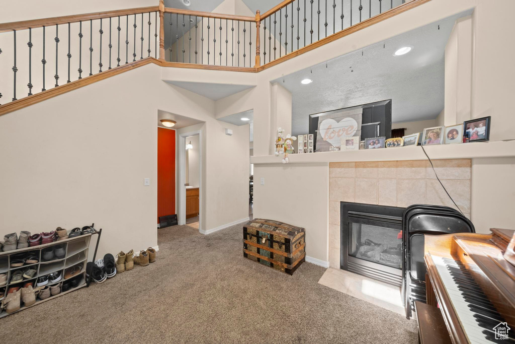 Living room featuring carpet flooring, a high ceiling, and a tile fireplace