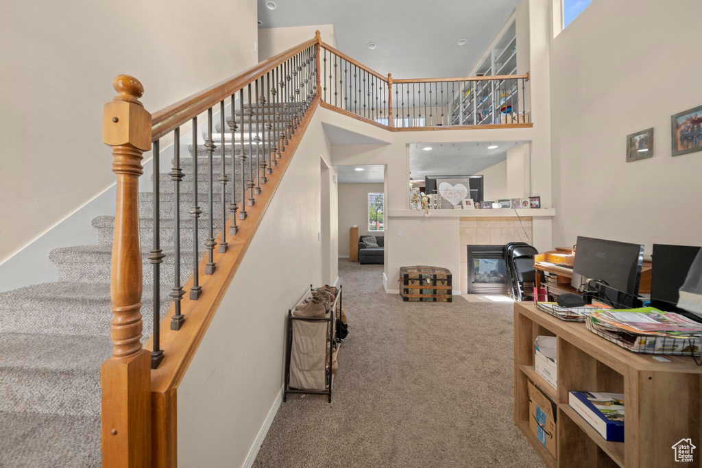 Stairs featuring a towering ceiling, carpet flooring, and a tile fireplace