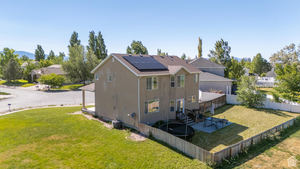 Back of property featuring a patio area, solar panels, and a yard