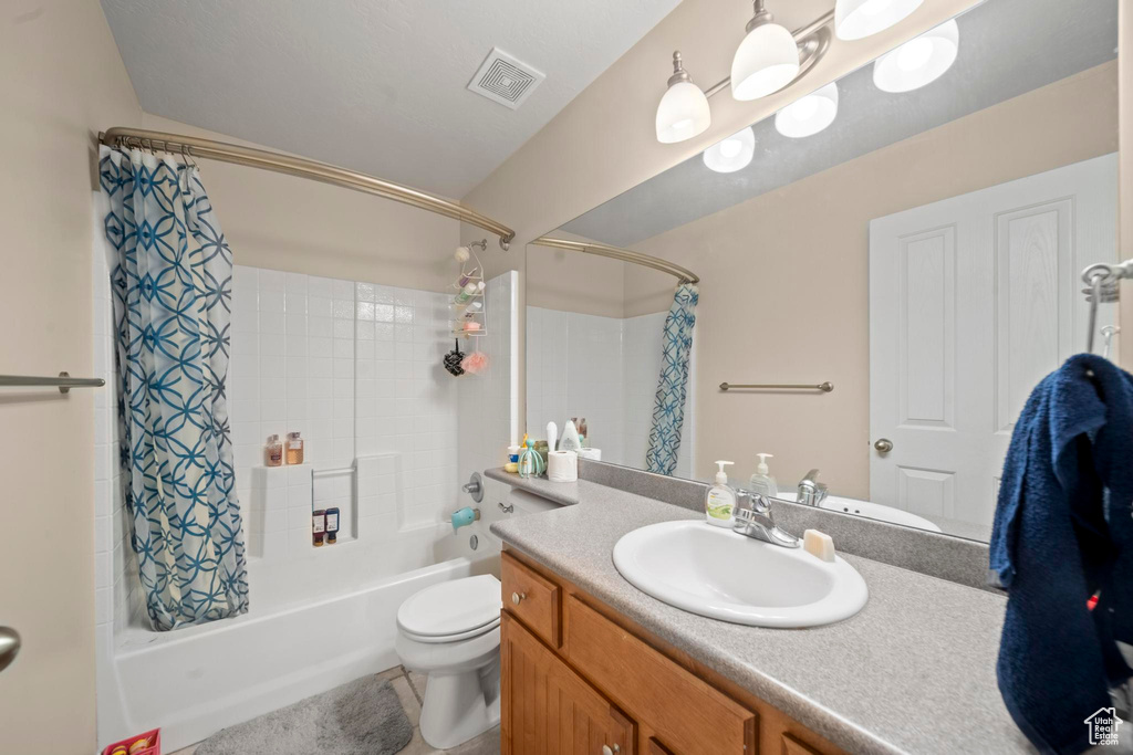 Full bathroom featuring shower / bathtub combination with curtain, toilet, and large vanity