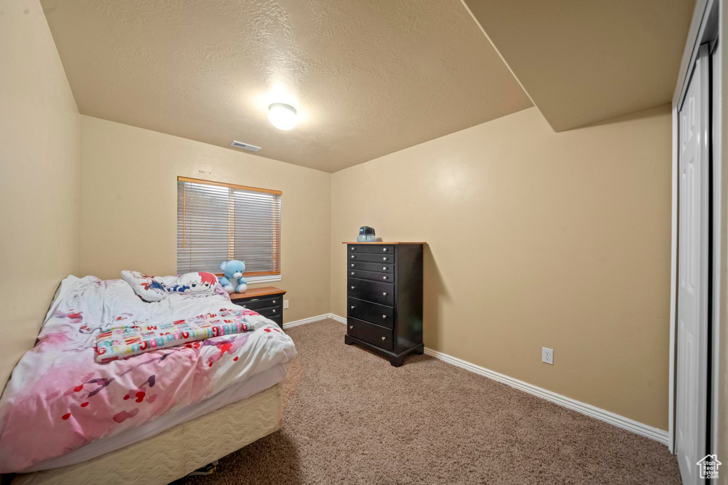 Bedroom with a textured ceiling and carpet