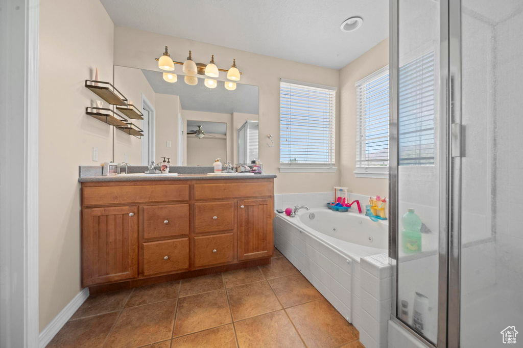 Bathroom featuring tile floors, shower with separate bathtub, double sink vanity, and ceiling fan