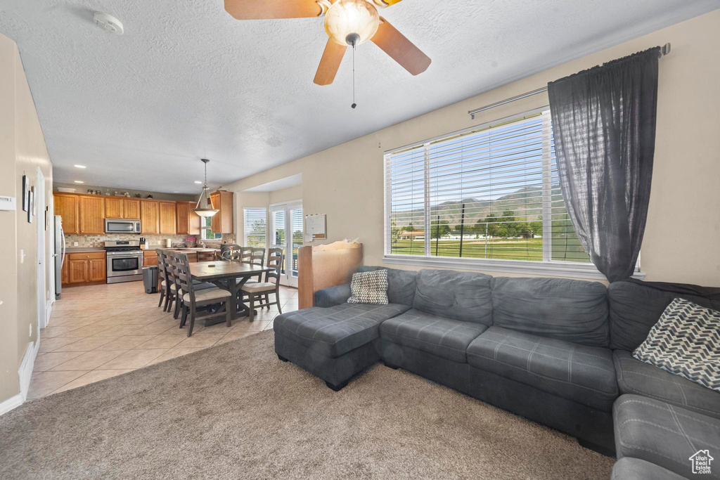 Carpeted living room with ceiling fan and a textured ceiling