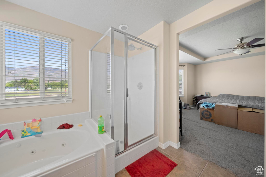 Bathroom featuring tile flooring, independent shower and bath, ceiling fan, and a textured ceiling