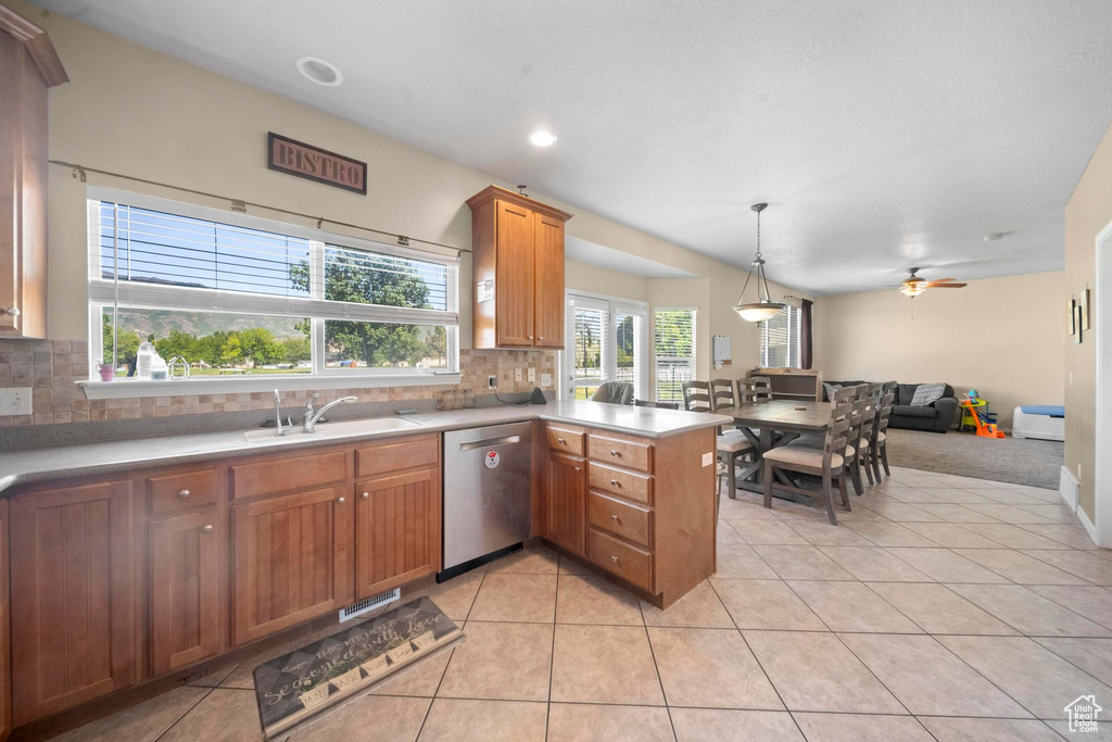 Kitchen featuring kitchen peninsula, decorative light fixtures, backsplash, sink, and dishwasher