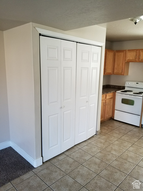 Kitchen featuring white range with electric cooktop and light tile floors