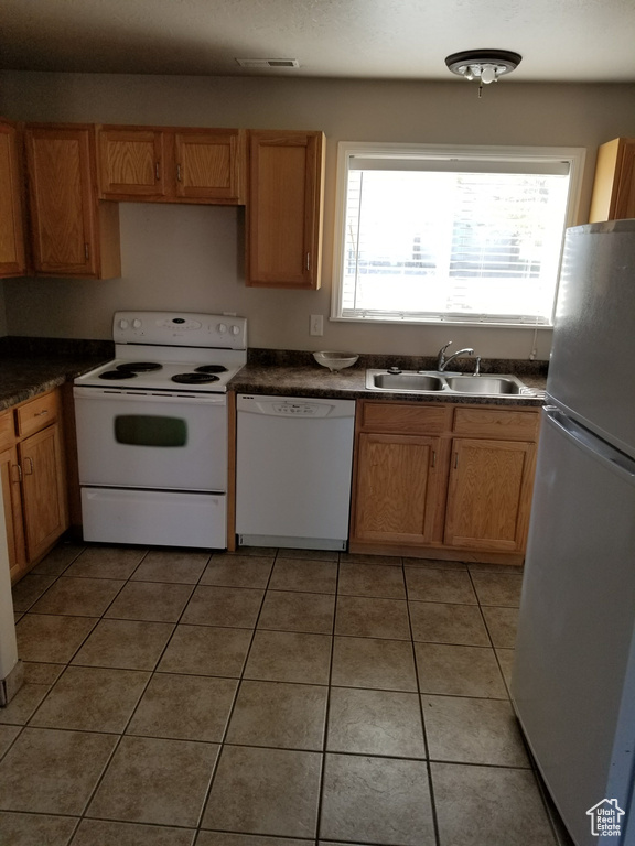 Kitchen with sink, white appliances, and light tile floors