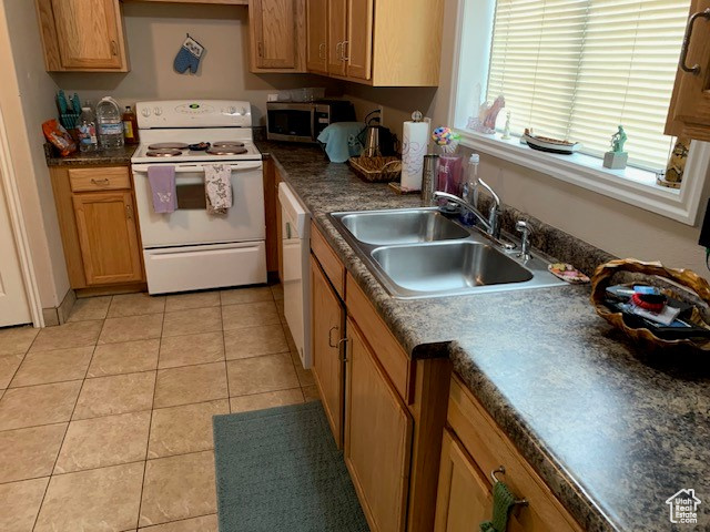 Kitchen with sink, white appliances, and light tile floors